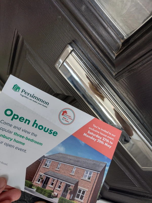Persimmon Homes flyer being pushed through a letter box as part of a leaflet drop campaign