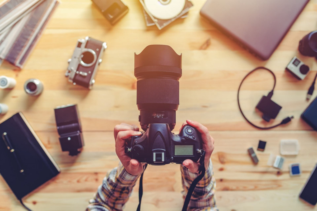 Top down view of a professional photographer holding a camera over a desk